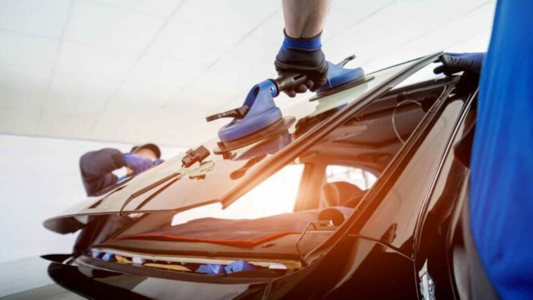 Car windshield being installed by technicians.